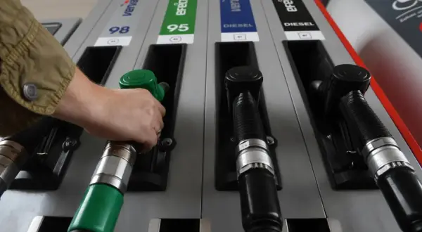 Ręka sięga po zieloną dyszę dystrybutora, obok czarne dysze do **diesel paliwo jak wygląda**.