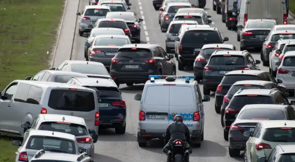 Korki na drodze ekspresowej. Policja próbuje opanować chaos, a motocyklista przeciska się między samochodami.