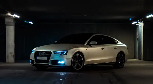 Białe Audi z niebieskimi światłami w garażu. Samochód powyżej 150 tys. a koszty utrzymania? Warto rozważyć.