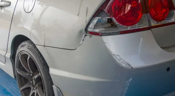 Uszkodzony tył samochodu po parkingowej stłuczce. Wgniecenie i liczne zarysowania lakieru, typowe dla szkody w leasingu.