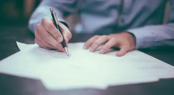 Ręka pisze na papierze, analizując jak odliczyć leasing od podatku przykład.