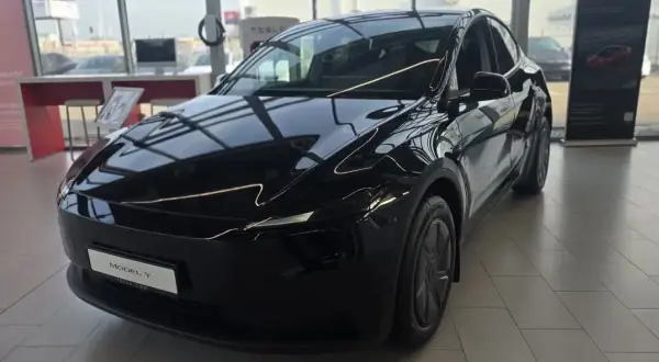 Błyszczący, czarny Tesla Model Y, idealny dla siedmioosobowej rodziny, stoi w salonie.