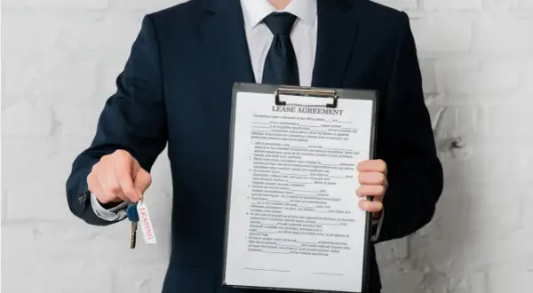 Biznesmen z umową leasingową i kluczami. Sprawdź, jak sprawdzić czy dostanę leasing, aby zacząć swoją drogę do posiadania wymarzonego pojazdu.
