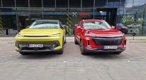 Dwa nowe chińskie samochody, żółty i czerwony, zaparkowane przed salonem BAIC w Europie.