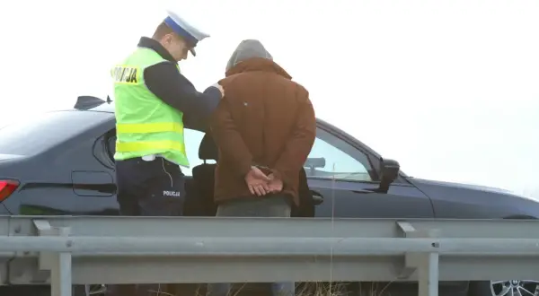 Policjant zakłada kajdanki zatrzymanemu mężczyźnie. Nowelizacja kodeksu karnego w praktyce.