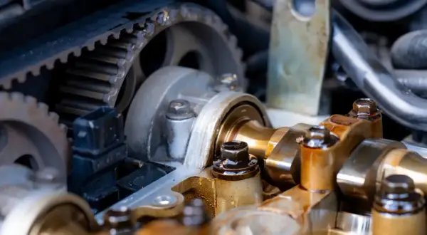 Widok na mechanizm rozrządu w aucie: pasek zębaty, koła zębate i wałek rozrządu.