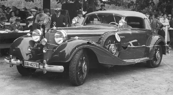 Elegancki, zabytkowy pierwszy mercedes z lat 30. XX wieku, z widoczną tablicą rejestracyjną IIA-42781, otoczony przez ludzi.
