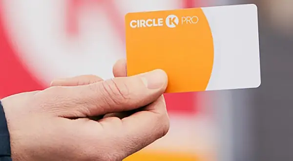 Dłoń trzyma pomarańczowo-białą kartę flotową Circle K PRO.