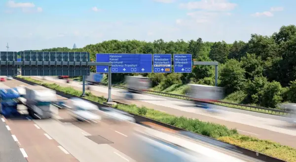 Autostrada w Niemczech, znaki drogowe wskazujące kierunki miast. Uważaj na odsetki za niezapłacony mandat w Niemczech, bo mogą Cię dogonić jak te ciężarówki.