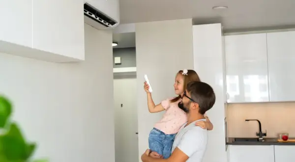 Ojciec z córką sterują klimatyzacją. Czy gaz z klimatyzacji jest szkodliwy dla zdrowia? Nowoczesne urządzenia są bezpieczne.