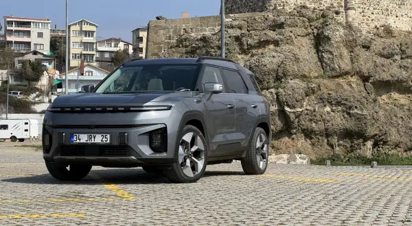 Nowy SsangYong elektryczny SUV stoi na parkingu przed kamiennym murem.