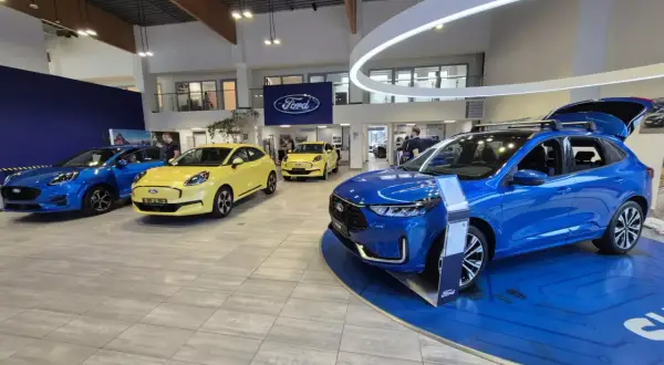Salon Forda z kilkoma nowymi autami, w tym niebieskim SUV-em. Zastanawiasz się, auto w leasingu co to znaczy? To opcja dla Ciebie!