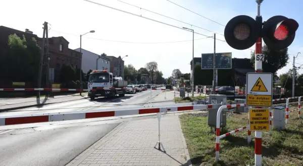 Przejazd kolejowy z opuszczonymi rogatkami i czerwonymi światłami. Kierowca ciężarówki może otrzymać mandat za przejazd kolejowy, jeśli zignoruje sygnały.