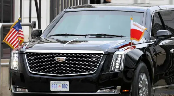 Czarne auto prezydenta USA, Cadillac Escalade, z flagami USA i Polski.