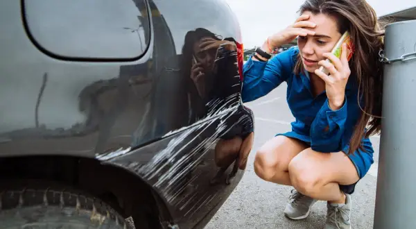 Zmartwiona kobieta dzwoni po pomoc po tym, jak jej auto w leasing ucierpiało w wyniku szkody z OC sprawcy.