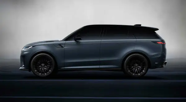 Elegancki, ciemnoszary land rover elektryczny z czarnymi felgami, poruszający się po ciemnej drodze.