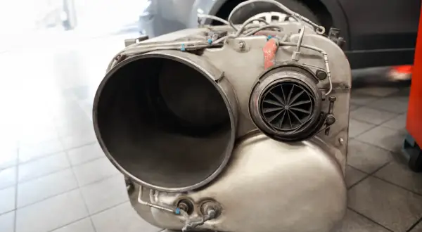 Metalowy element układu wydechowego, prawdopodobnie turbosprężarka lub katalizator, leży na podłodze. Brak DPF może skutkować mandatem.