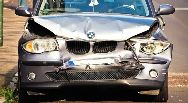 Uszkodzony BMW po wypadku. Zderzak, maska i reflektory są zniszczone. Wygląda na to, że czeka go szkoda całkowita, mimo że był w leasingu.