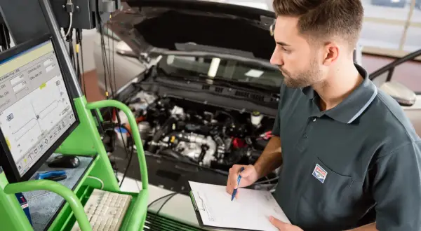 Mechanik sprawdza wyniki diagnostyki komputerowej podczas pierwszego przeglądu gwarancyjnego samochodu.