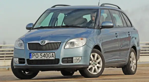 Niebieska Skoda Fabia Combi, idealne jakie auto rodzinne, z kierowcą za kierownicą, na tle jasnego nieba.