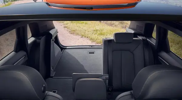 Widok z bagażnika na tylne siedzenia i otwartą klapę. Wnętrze Audi Q3 gotowe na podróż.