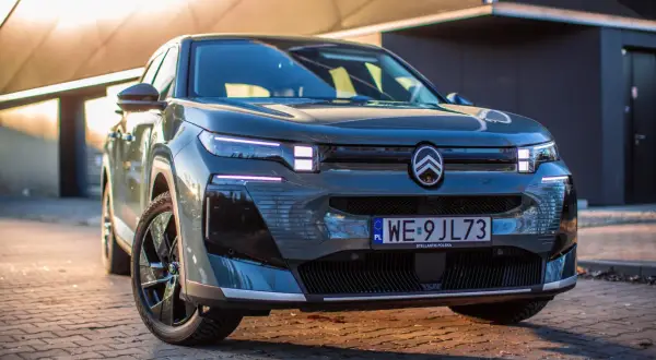 Nowoczesny, ciemnoszary francuski samochód z charakterystycznym logo Citroëna na masce, zaparkowany na brukowanej nawierzchni.