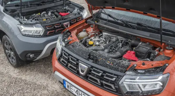 Dwa silniki Dacia Duster, szary i pomarańczowy, z otwartymi maskami. Który wybrać: diesel czy benzyna?