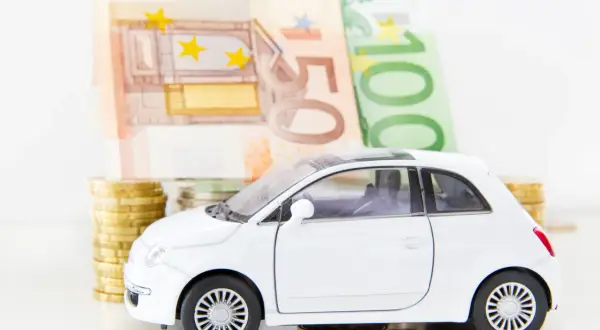 Biały samochodzik na monetach i banknotach euro. Zastanawiasz się, co z leasingiem po zamknięciu firmy?