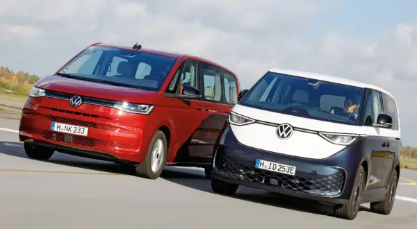 Dwa minivany Volkswagen: czerwony i dwukolorowy, jadące po drodze.