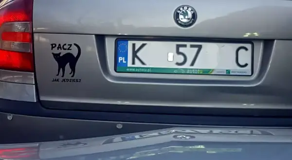 Czarny kot na klapie bagażnika z napisem "PACZ JAK JEDZIESZ". Tablica rejestracyjna K 57 C.