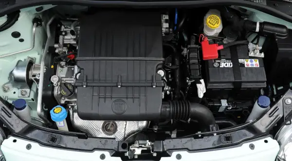 Silniki Fiata 500 w komorze silnika. Widoczny czarny plastikowy element z logo FIAT, akumulator i płyny eksploatacyjne.