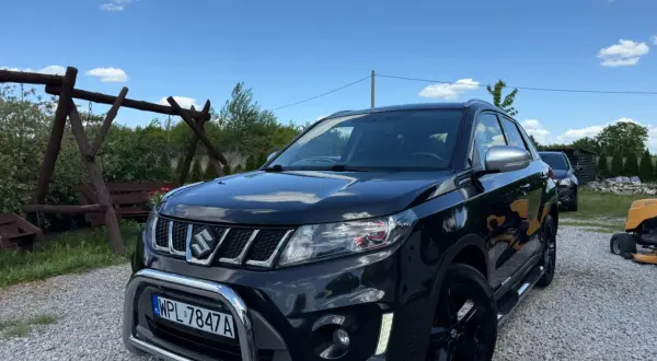 Czarny Suzuki Vitara 1.4 Boosterjet, z chromowanym grillem i zderzakiem, stoi na żwirze. Czyżby awarie?