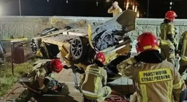 Strażacy pracują przy wraku żółtego samochodu po wypadku Patryka Peretti. Auto jest mocno zniszczone, leży na boku.