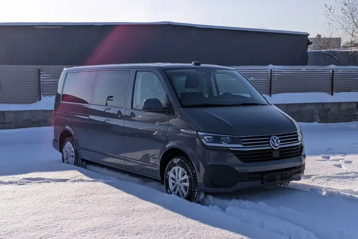 Szare auto 9 osobowe w zimowej scenerii, zaparkowane na śniegu.
