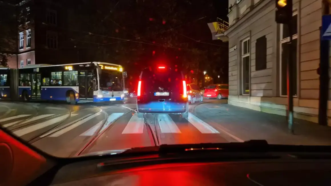 Nocne miasto, tramwaje i samochody. Nagłe hamowanie przepisów ruchu drogowego, gdy kierowca widzi czerwone światło.