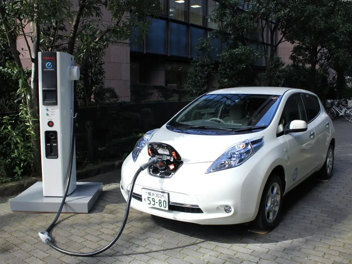 Biały Nissan Leaf podłączony do ładowarki. To przyszłość, czyli serwis samochodów elektrycznych.