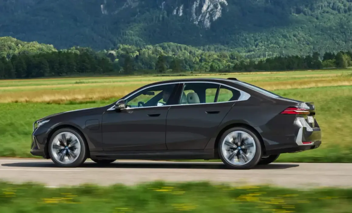 Ciemny sedan BMW jedzie przez malowniczy krajobraz. Idealny do biznesu, gdy rozważasz odliczenie VAT od leasingu samochodu osobowego powyżej 150 tys.