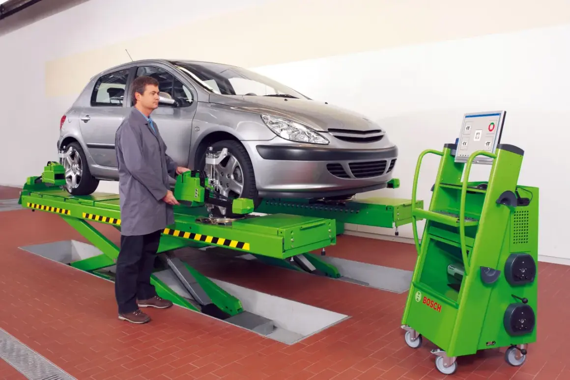 Mechanik sprawdza zbieżność kół samochodu na podnośniku, używając zaawansowanego sprzętu do pomiaru geometrii.