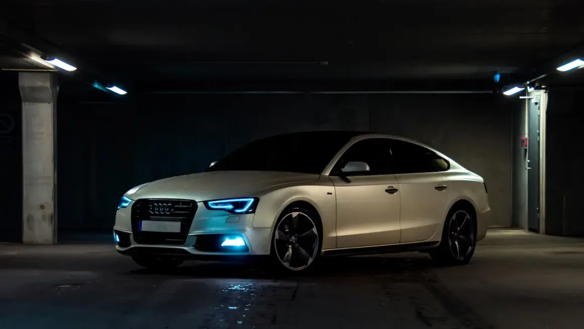 Białe Audi z niebieskimi światłami w garażu. Samochód powyżej 150 tys. a koszty utrzymania? Warto rozważyć.