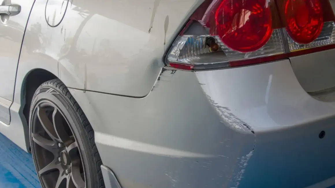 Uszkodzony tył samochodu po parkingowej stłuczce. Wgniecenie i liczne zarysowania lakieru, typowe dla szkody w leasingu.