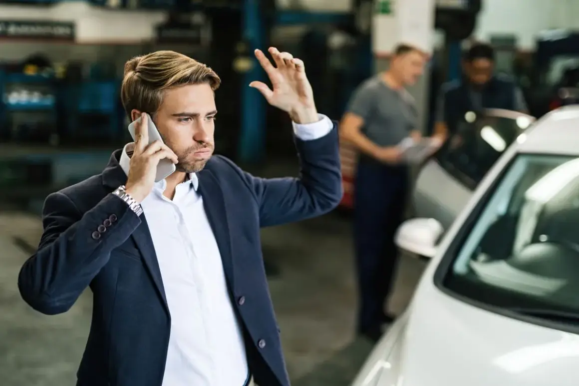 Mężczyzna w garniturze rozmawia przez telefon, martwiąc się o ubezpieczenie samochodu w leasingu.