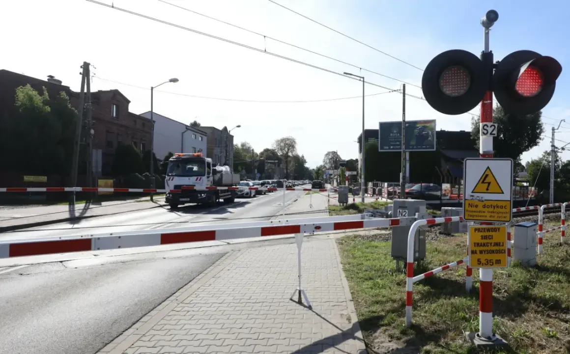 Przejazd kolejowy z opuszczonymi rogatkami i czerwonymi światłami. Kierowca ciężarówki może otrzymać mandat za przejazd kolejowy, jeśli zignoruje sygnały.