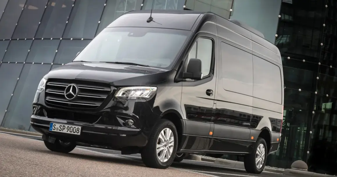 Czarny Mercedes-Benz Sprinter, jeden z najlepszych samochodów dostawczych, zaparkowany przed nowoczesnym budynkiem.