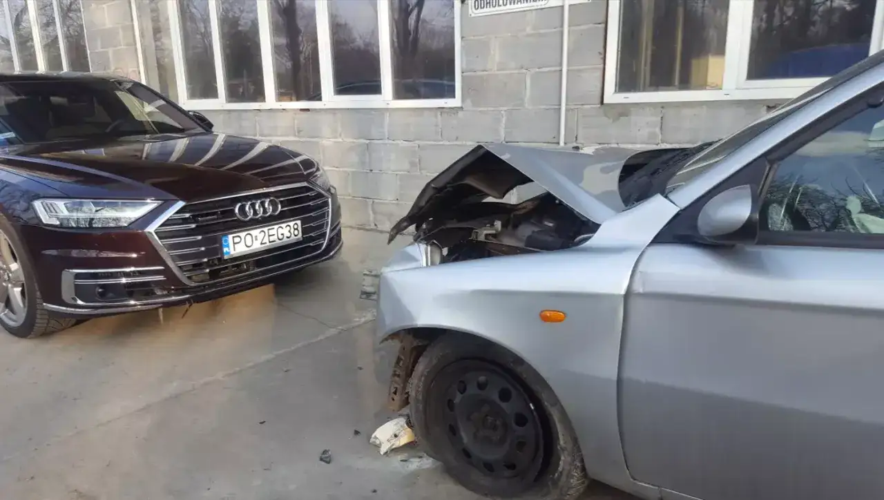 Auto w leasingu uszkodzone. Szkoda z OC sprawcy, przód srebrnego auta zniszczony, maska otwarta.