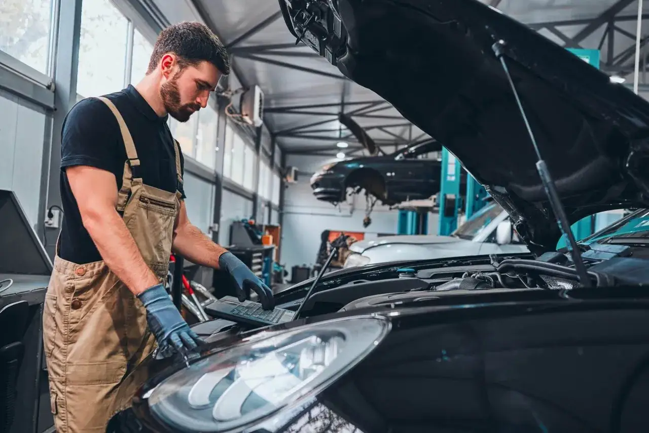 Mechanik diagnozuje problem, gdy auto gaśnie podczas jazdy. Podłączony komputer pokazuje błędy silnika.