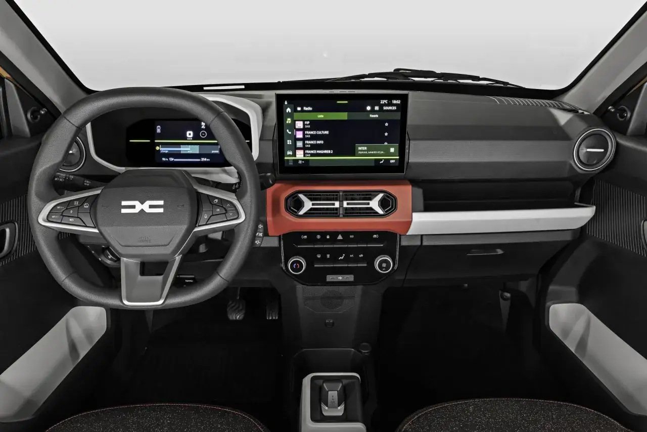 Wnętrze Dacii Spring. Cyfrowy kokpit i ekran multimediów pokazują dane o zasięgu i stacjach radiowych. Dacia Spring wymiary są kompaktowe, idealne do miasta.
