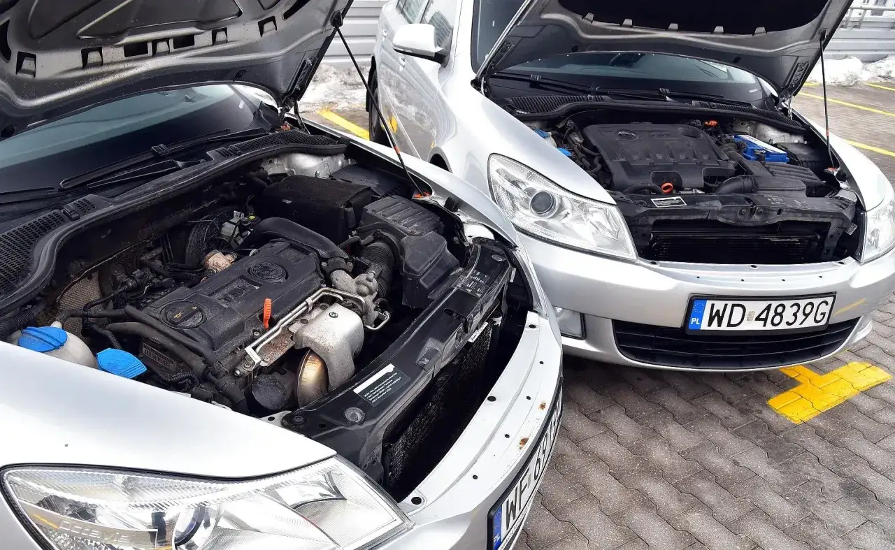Dwa srebrne samochody z otwartymi maskami. Jeden silnik wygląda na diesla, drugi na benzynę. Dylemat wyboru: diesel czy benzyna?