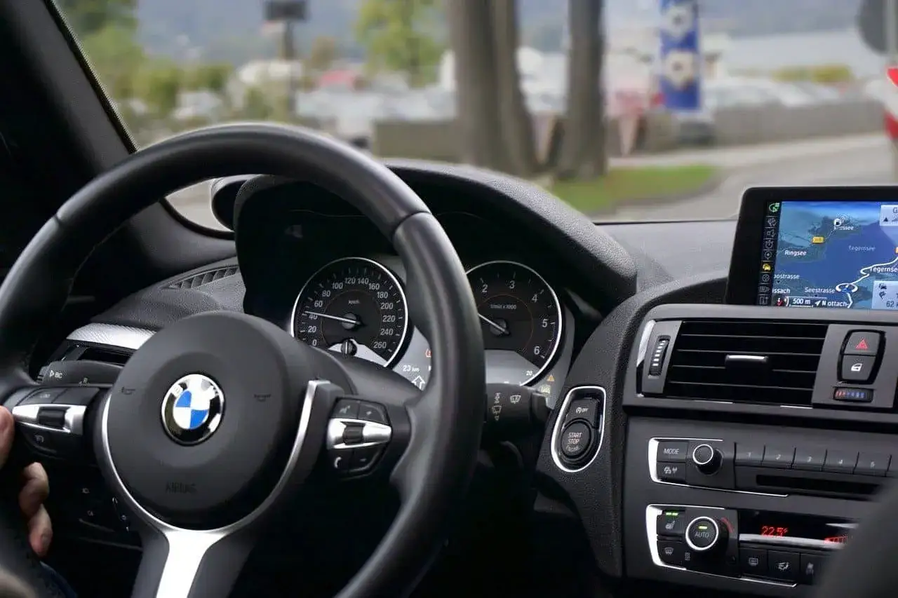 Wnętrze BMW z nawigacją. Rozważasz wynajem samochodu osobowego a koszty? Sprawdź, co wpływa na cenę.