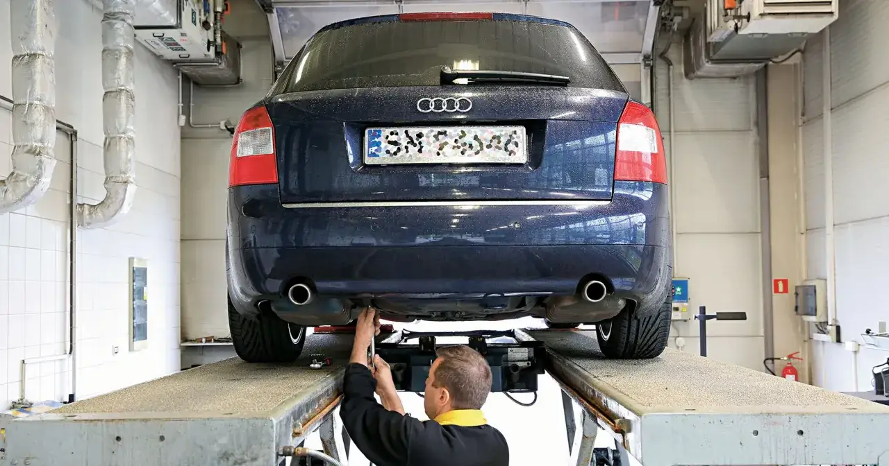 Mechanik wykonuje serwisowanie samochodu Audi na podnośniku.