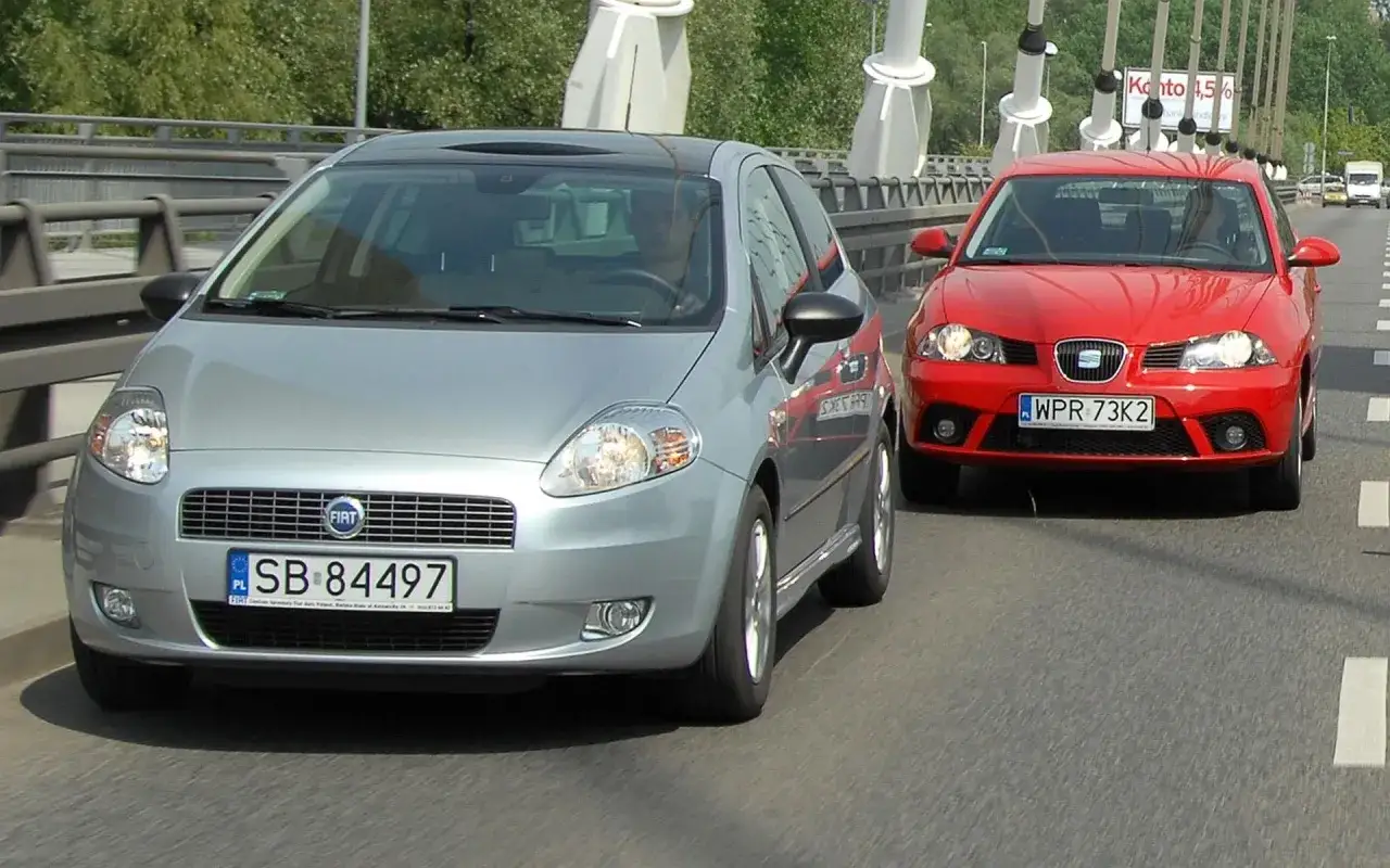 Srebrny Fiat i czerwony Seat jadą obok siebie. To ich pierwszy samochód, który zabiera ich na przygodę.